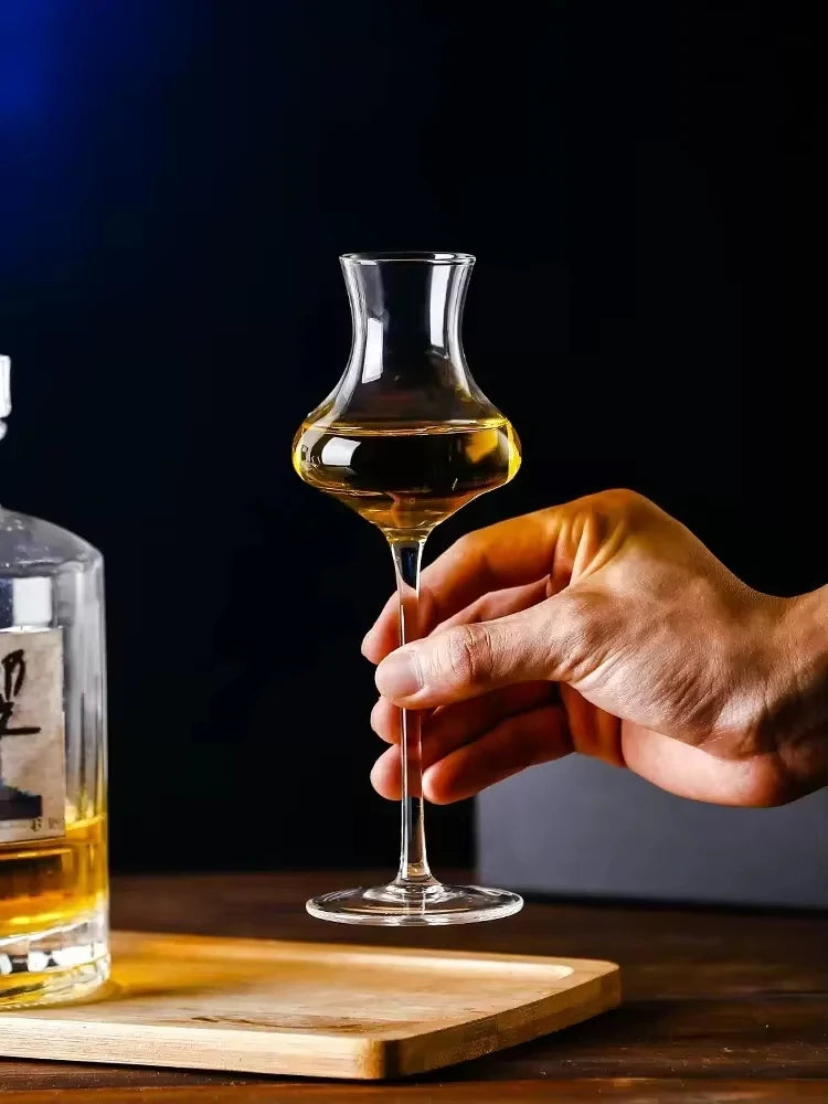  Hand holding a "Slender" crystal spirits glass alongside a bottle, sleek elongated silhouette — CL House Drinkware collection