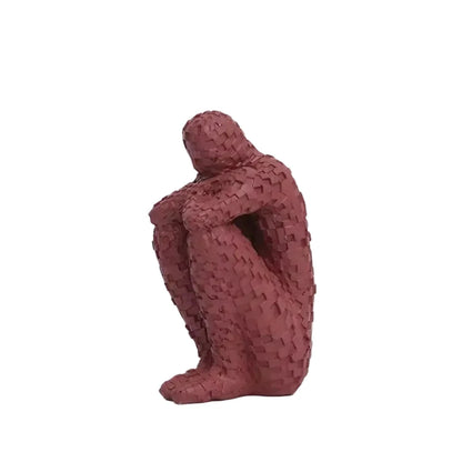 Red mosaic resin figure sculpture in a seated, contemplative pose on a white background.