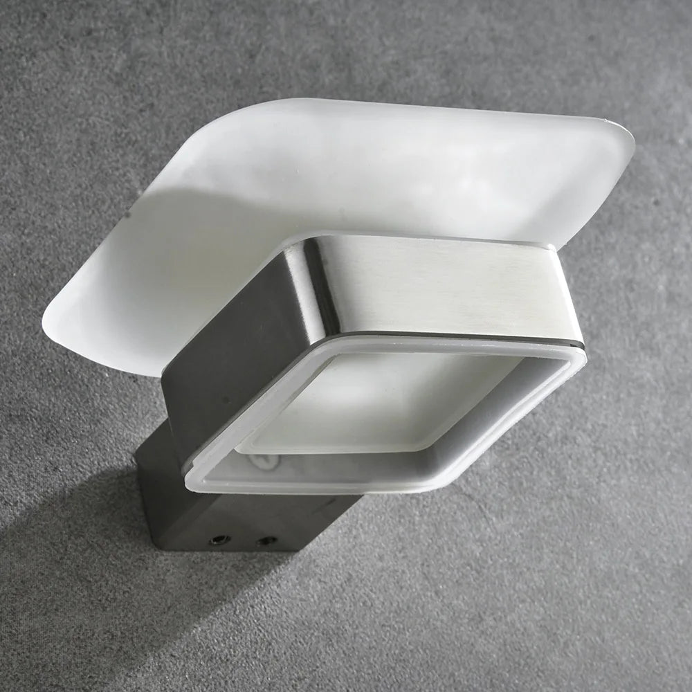 Close-up detail of wall-mounted frosted glass soap dish showing brushed nickel stainless steel bracket and mounting screws on grey concrete wall