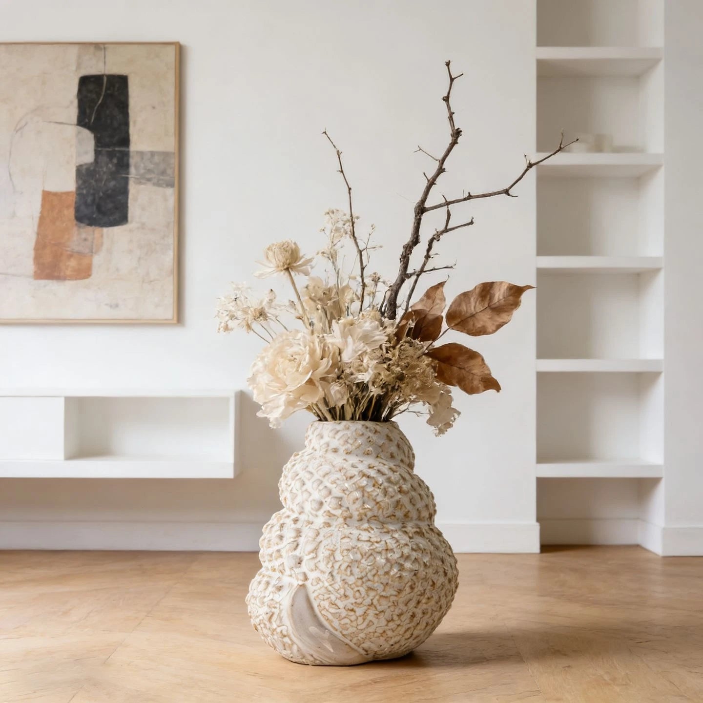Coral Nest textured ceramic vase styled with dried white roses and bare branches on wooden floor, abstract art and white shelving background