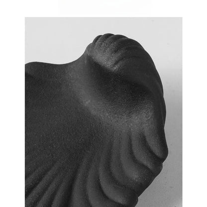 Close-up detail of midnight black matte ceramic shell soap dish showing sandy unglazed texture and sculpted ridges