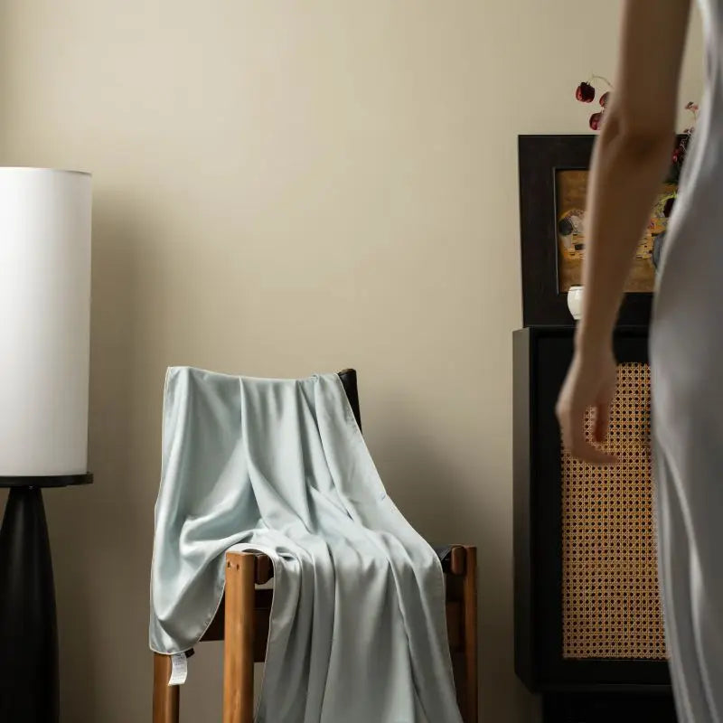 Mist Blue 100% Tencel cooling summer blanket draped over an armchair in a styled living room
