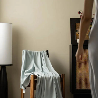Mist Blue 100% Tencel cooling summer blanket draped over an armchair in a styled living room