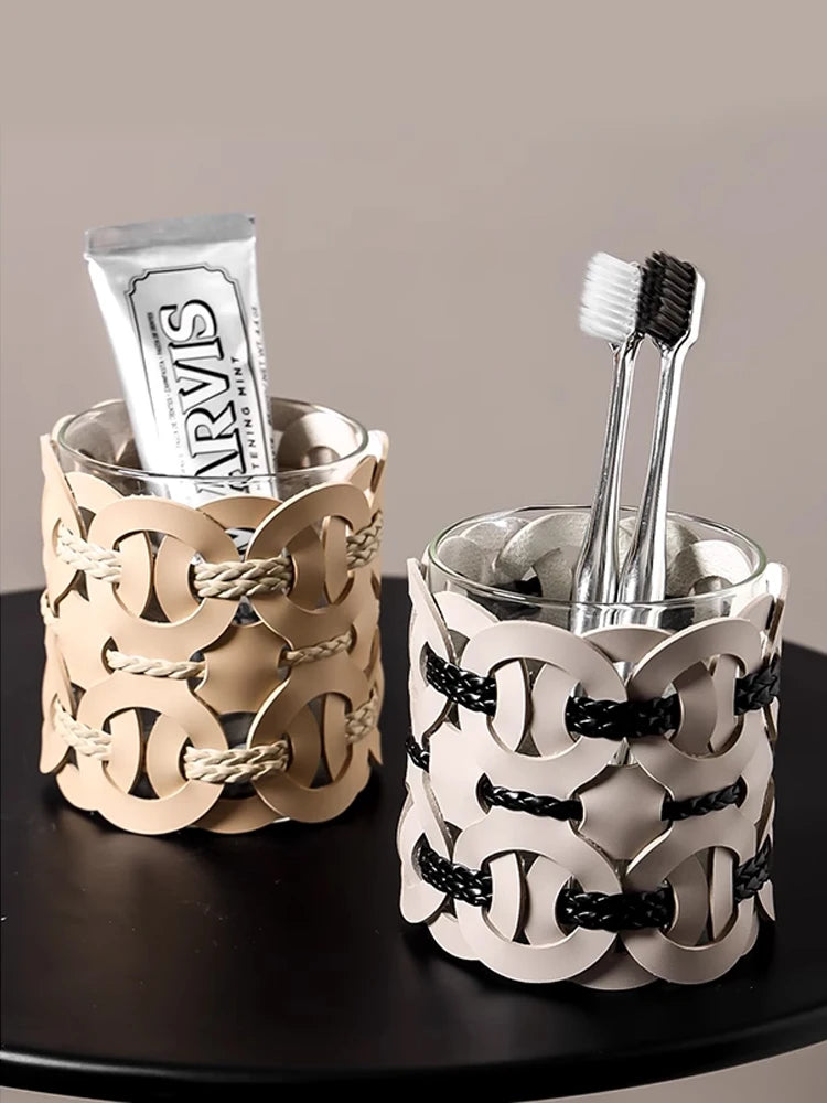 Cognac Weave and Ivory Weave woven leather bathroom organisers on dark tray — Cognac Weave holding a tube of Marvis toothpaste, Ivory Weave holding silver toothbrushes