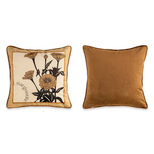 "Marguerite" botanical velvet cushion cover front and back view, warm caramel ground with bold black ink botanical illustration of zinnia flowers, cursive "marguerite" script in corner, plain caramel velvet reverse with coordinating piping — CL House Cushions collection