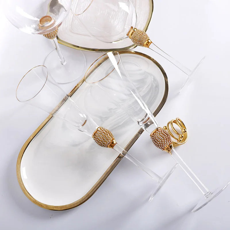 "Golden Jewel" crystal glasses with micro-crystal bead stems laid on a gold-rimmed ceramic tray, styled on a white marble surface