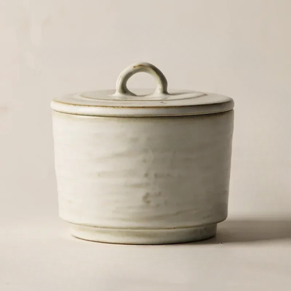 Matte off-white ceramic lidded bowl with loop handle, brushstroke glaze texture on neutral beige background — Stone Broth Ceramic Lidded Bowl by CL House