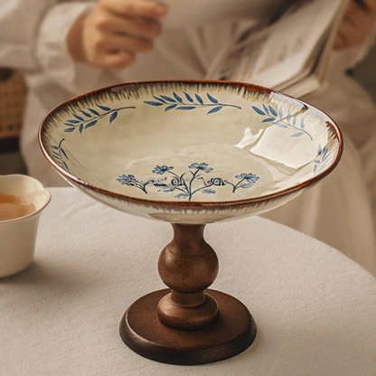 "Blue Botanics" Blue Freesia ceramic pedestal serving stand on a linen-covered table, styled with a tea cup — lifestyle shot with soft natural light