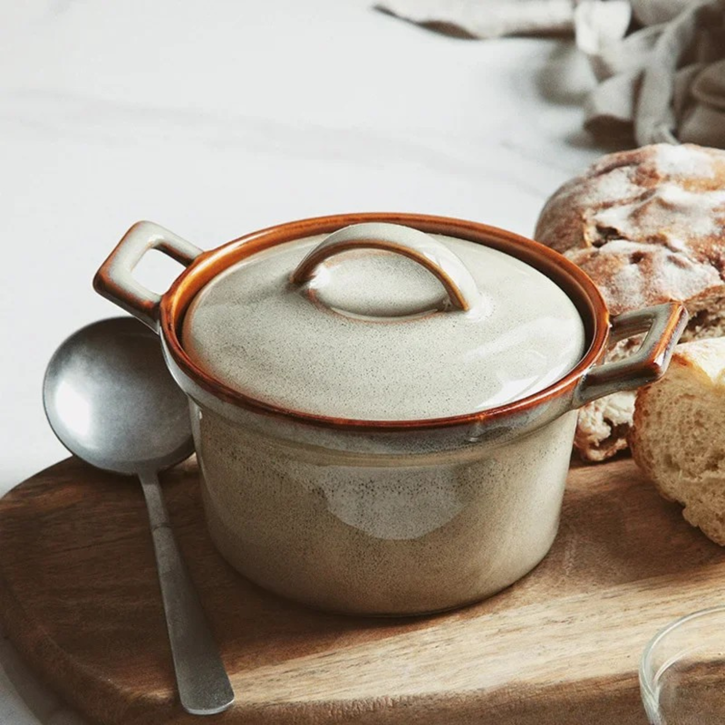  Sand Stone ceramic casserole with lid, styled on wooden board with vintage spoon and artisan sourdough bread, cream speckled glaze with amber rim — Stone Vessel by CL House
