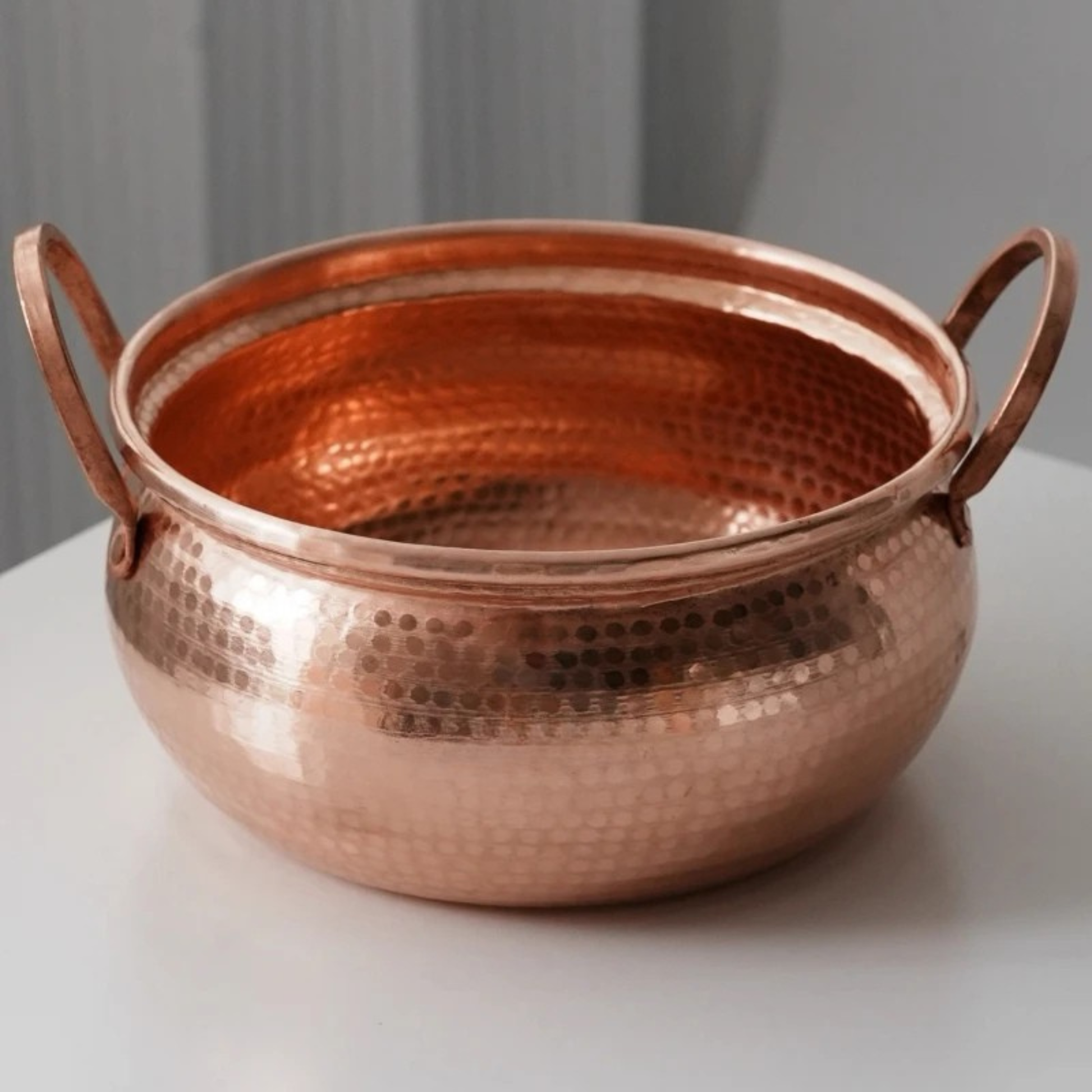 Copper Cauldron handmade pure copper stew pot without lid on a white surface, showing the open interior with hammer-textured rose-gold finish and two arched copper handles