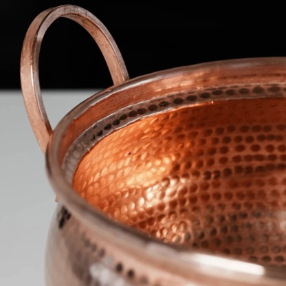 Copper Cauldron close-up interior view showing the deep hand-hammered pure copper texture inside the pot and the arched copper handle detail, with warm rose-gold tones