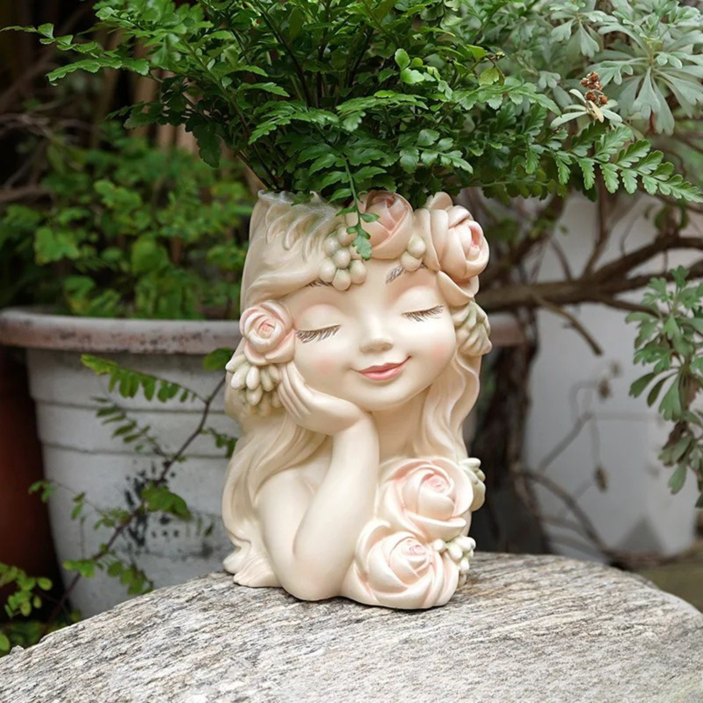 "Rose Muse" resin fairy head planter in Blush Cream — full body view styled with maidenhair fern on a stone surface in a garden