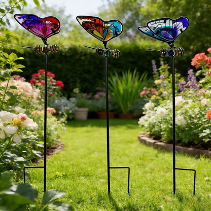 "Garden Wings" set of 3 stained glass effect metal butterfly garden stakes in pink-red, multicolour and blue tones, displayed in a lush English cottage garden with roses and wildflowers