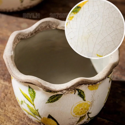 "Lemon Grove" ceramic plant pot close-up showing crackle glaze texture detail, hand-painted yellow lemon and green leaf print, unglazed interior and wavy scalloped rim, top-down view

