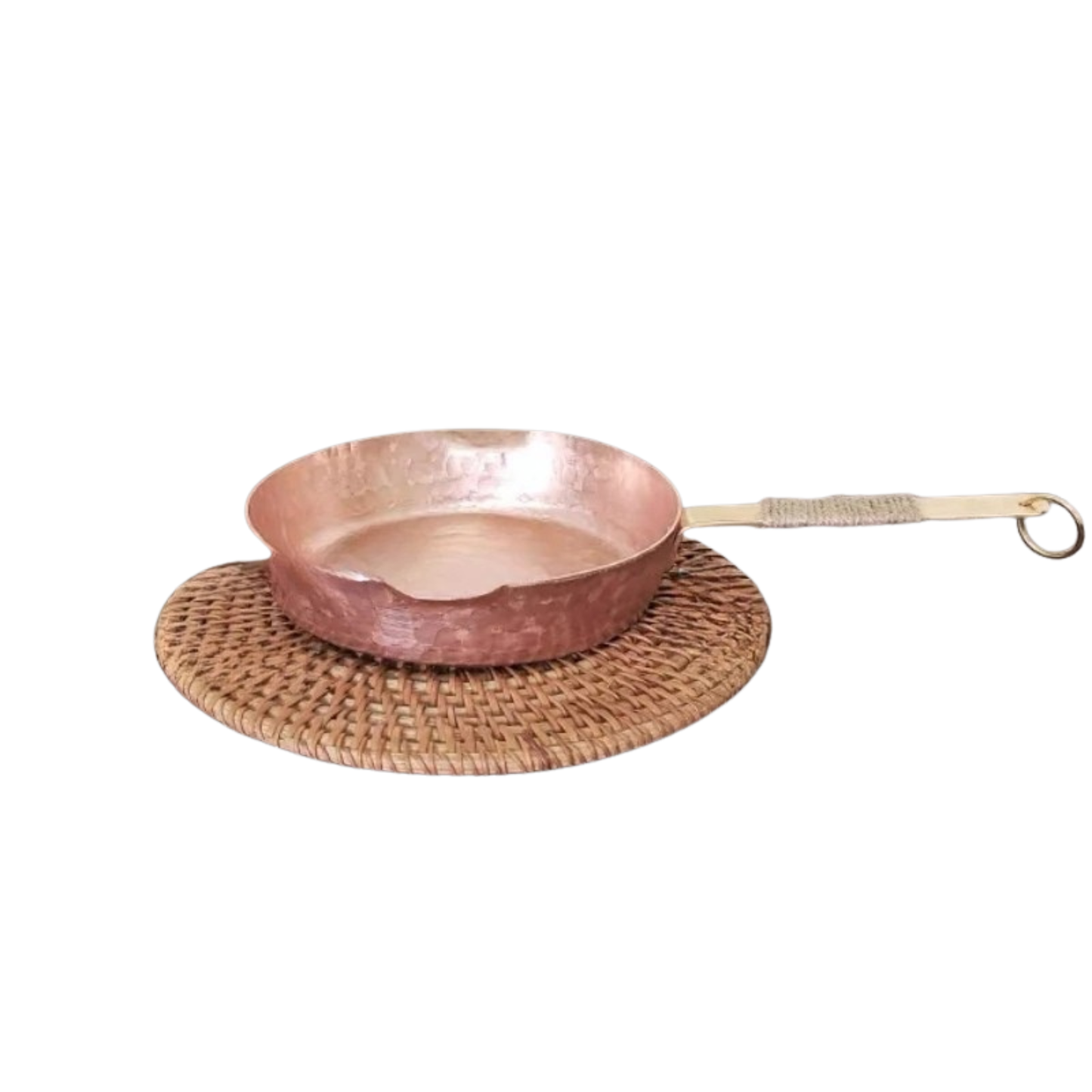 Copper Skillet handmade pure copper frying pan resting on a round rattan trivet, showing the hammer-textured rose-gold surface and brass jute-wrapped handle with ring hook