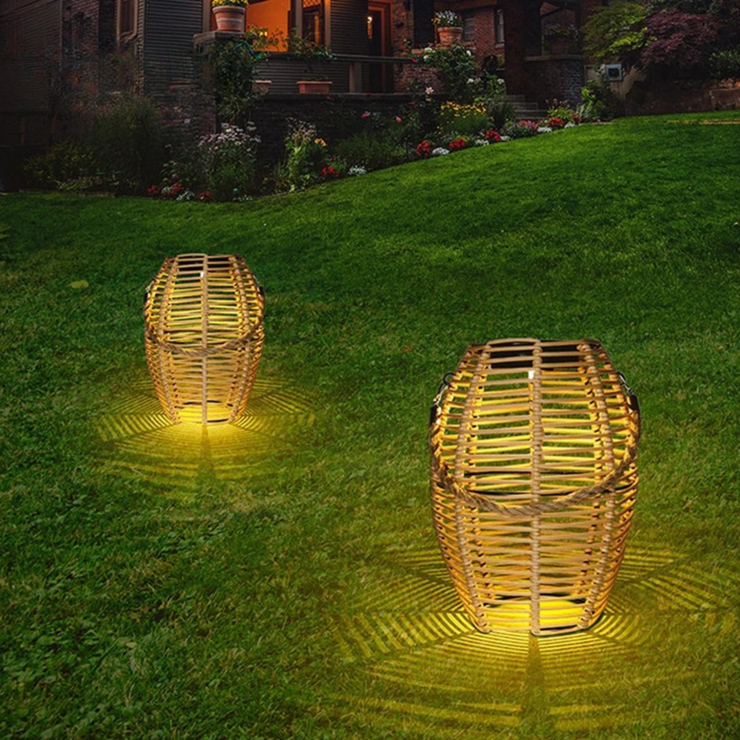 Two rattan solar lanterns glowing with warm amber light on a garden lawn at night, casting decorative shadow patterns on the grass