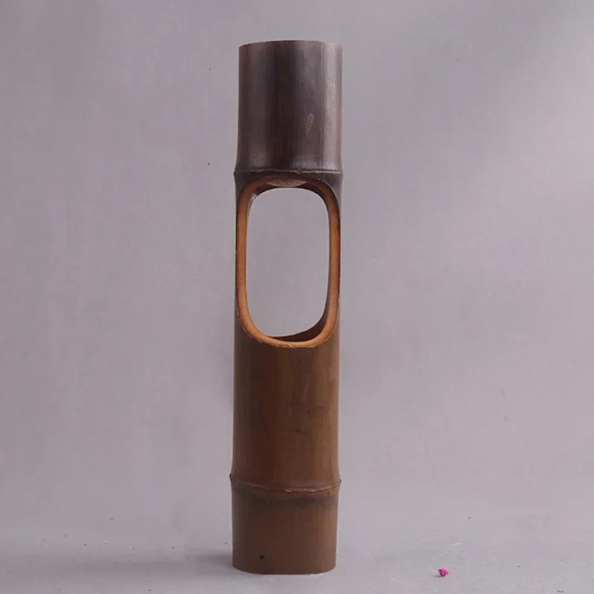 Handmade dark bamboo cylindrical vase with oval cut-out opening, natural bamboo texture, grey background