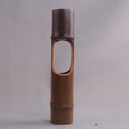 Handmade dark bamboo cylindrical vase with oval cut-out opening, natural bamboo texture, grey background