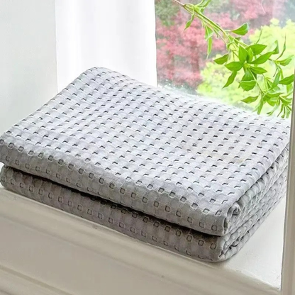 "100% Bamboo Fibre waffle-texture cooling blanket in Slate Grey — neatly folded on a white windowsill with natural light, soft and breathable summer bedding"