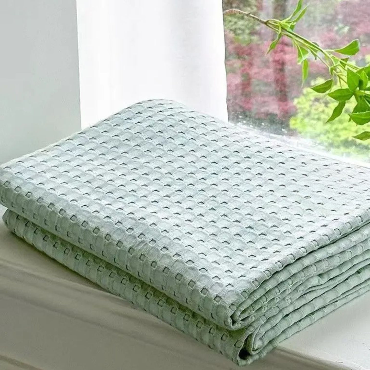 "100% Bamboo Fibre waffle-texture cooling blanket in Sage Mist — neatly folded on a white windowsill with natural light, soft and breathable summer bedding"
