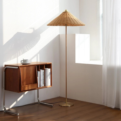 "Cone & Brass" floor lamp with natural rattan shade beside a wooden bookshelf in a sunlit white corner