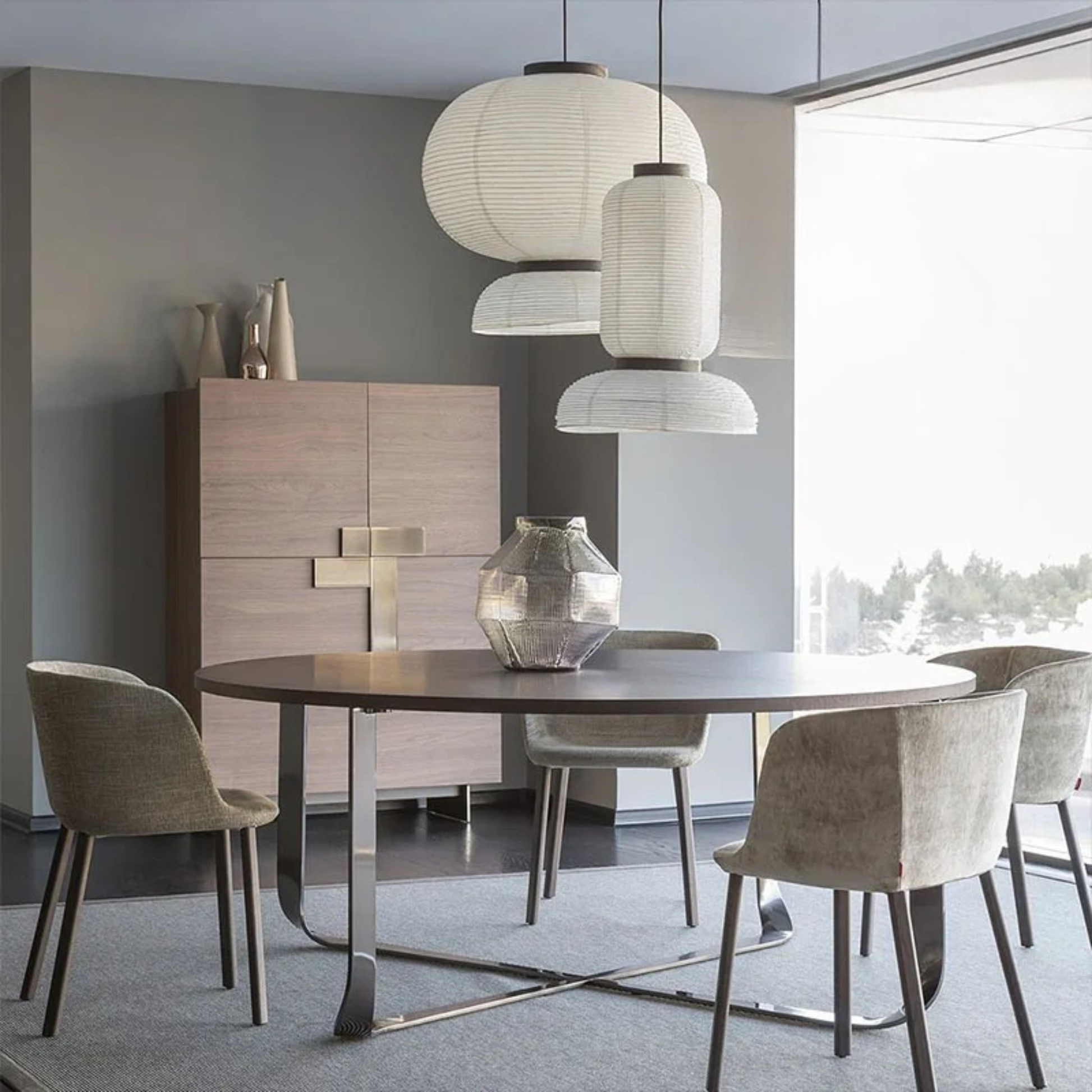 Three Rice & Ripple paper pendant lights clustered at different heights above a round dining table in a modern japandi dining room with grey walls and natural light