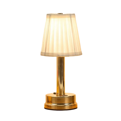  Gold rechargeable touch table lamp with pleated fabric shade glowing warm white on a wooden surface, against a neutral background

Manda a próxima! 📸