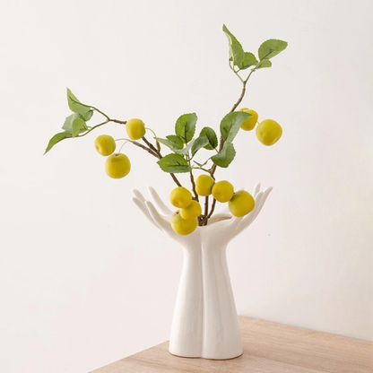 Open Hands white ceramic vase styled with yellow cherry blossom branches beside framed artwork, white background
