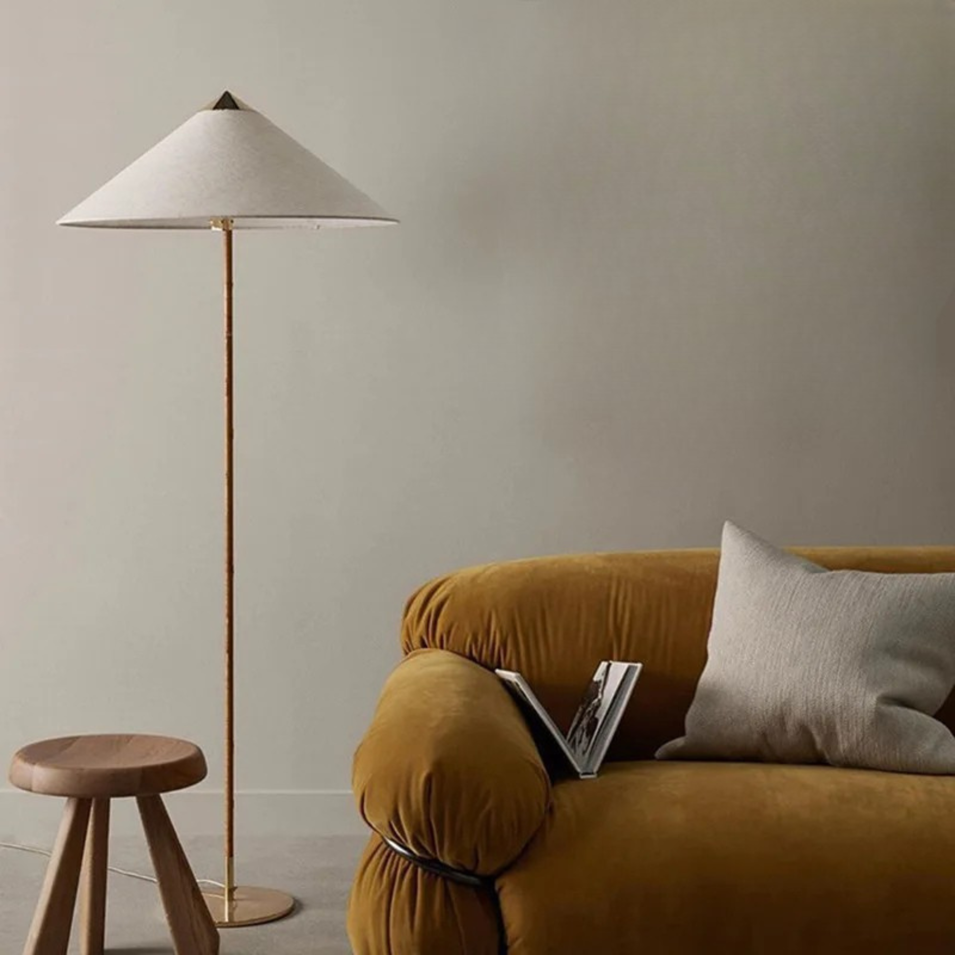 "Cone & Brass" floor lamp with linen shade beside a mustard velvet sofa and textured wall art in a warm living room