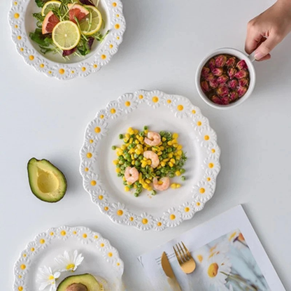 "Daisy Bloom" ceramic dinnerware set — top view styled table with shrimp and vegetable dish on big plate, citrus salad in bowl, fresh daisy flower and avocado on white surface with gold cutlery — lifestyle shot